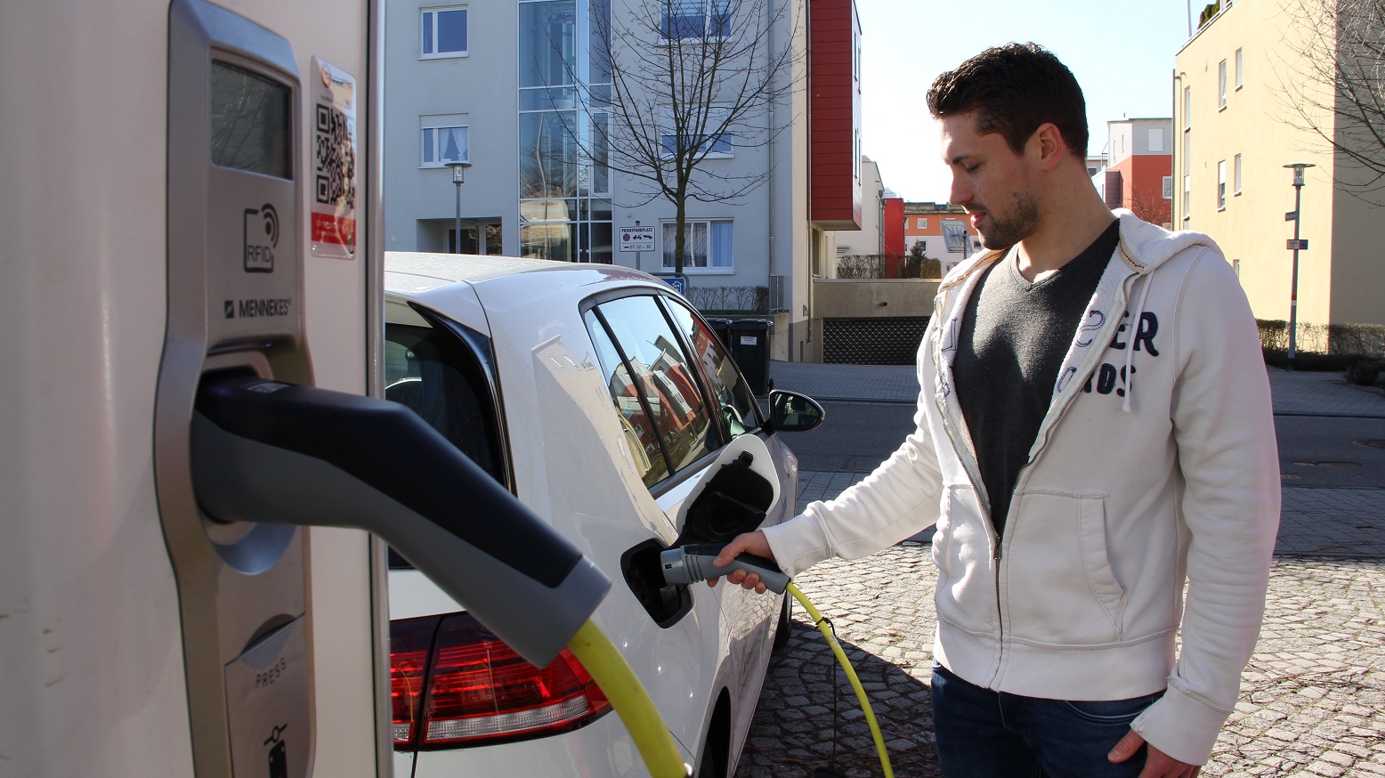 young man charges his car at E-charging point young man charges his car at E-charging point