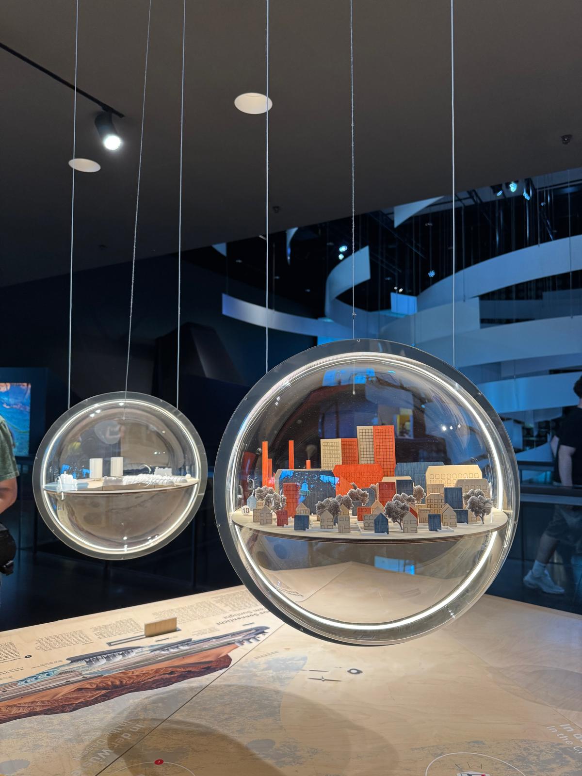 Ausstellung im Fururium: gläserne Kugeln mit Modellen von Städten hängen von der Decke
