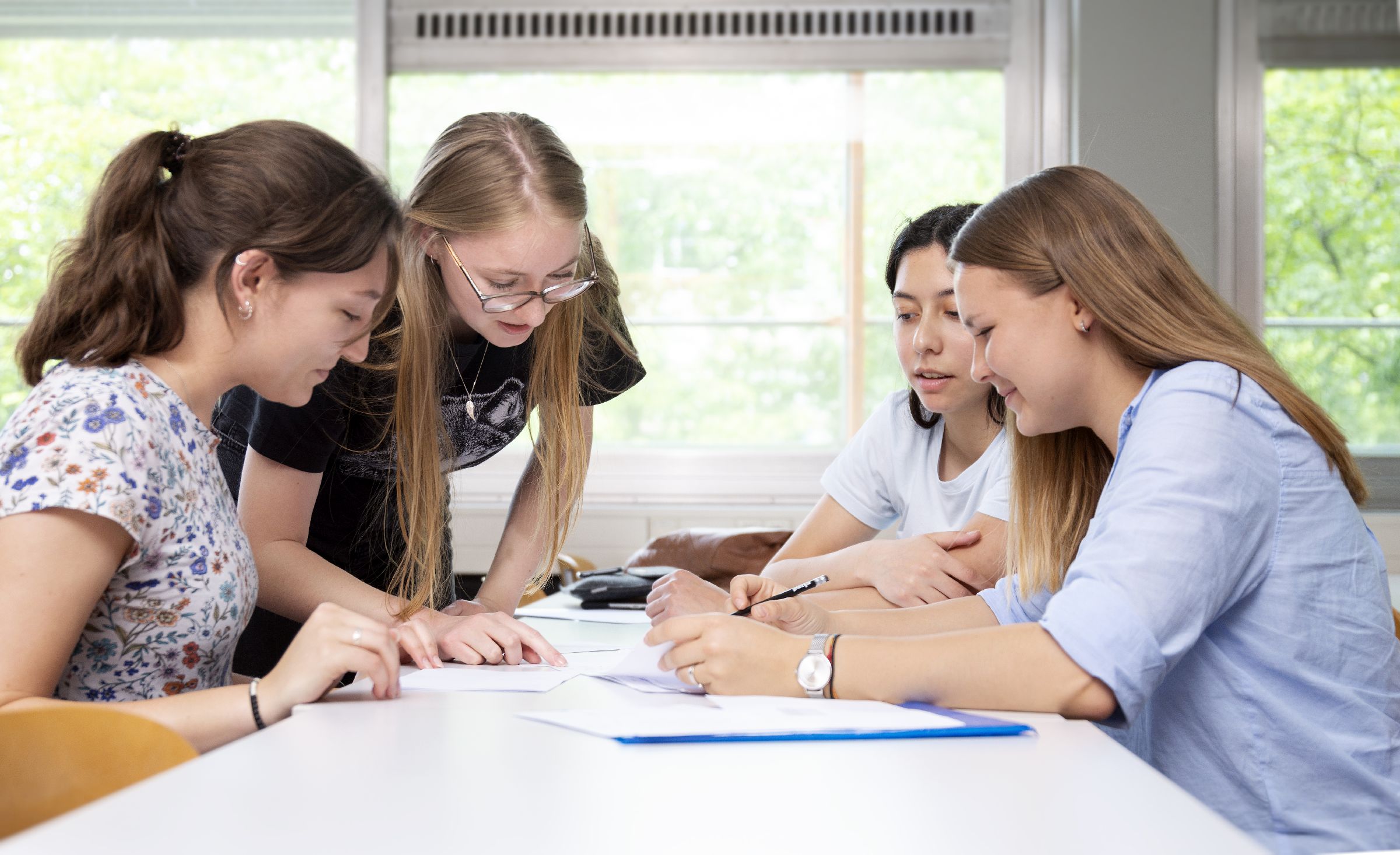 young women grouped around a table, discussing