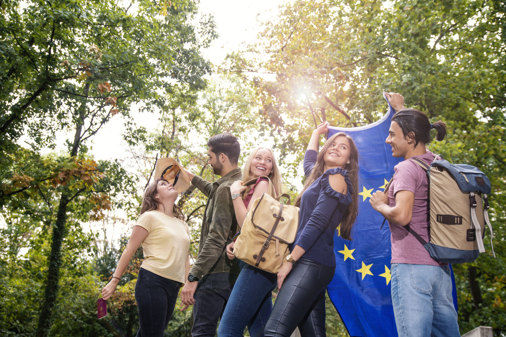 Students with backpacks, waving and holding the EU flag