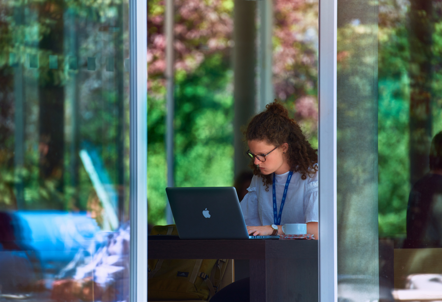 CERN Praktikantin am Laptop mit blauem CERN-Anhänger