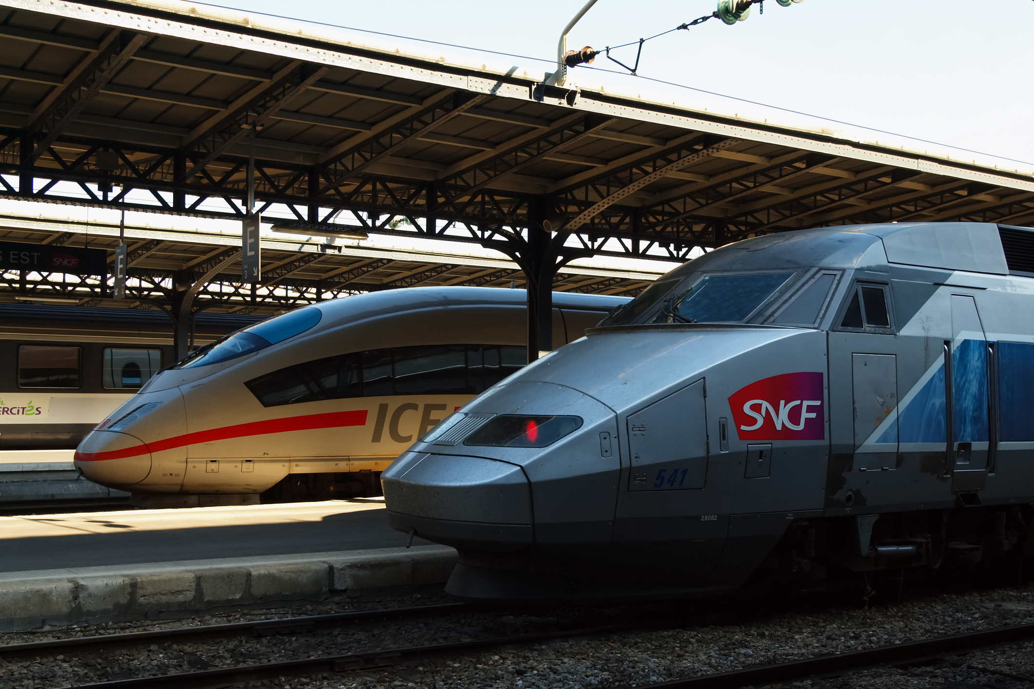 A German ICE and a French TGV train standing next to each other at a train station.