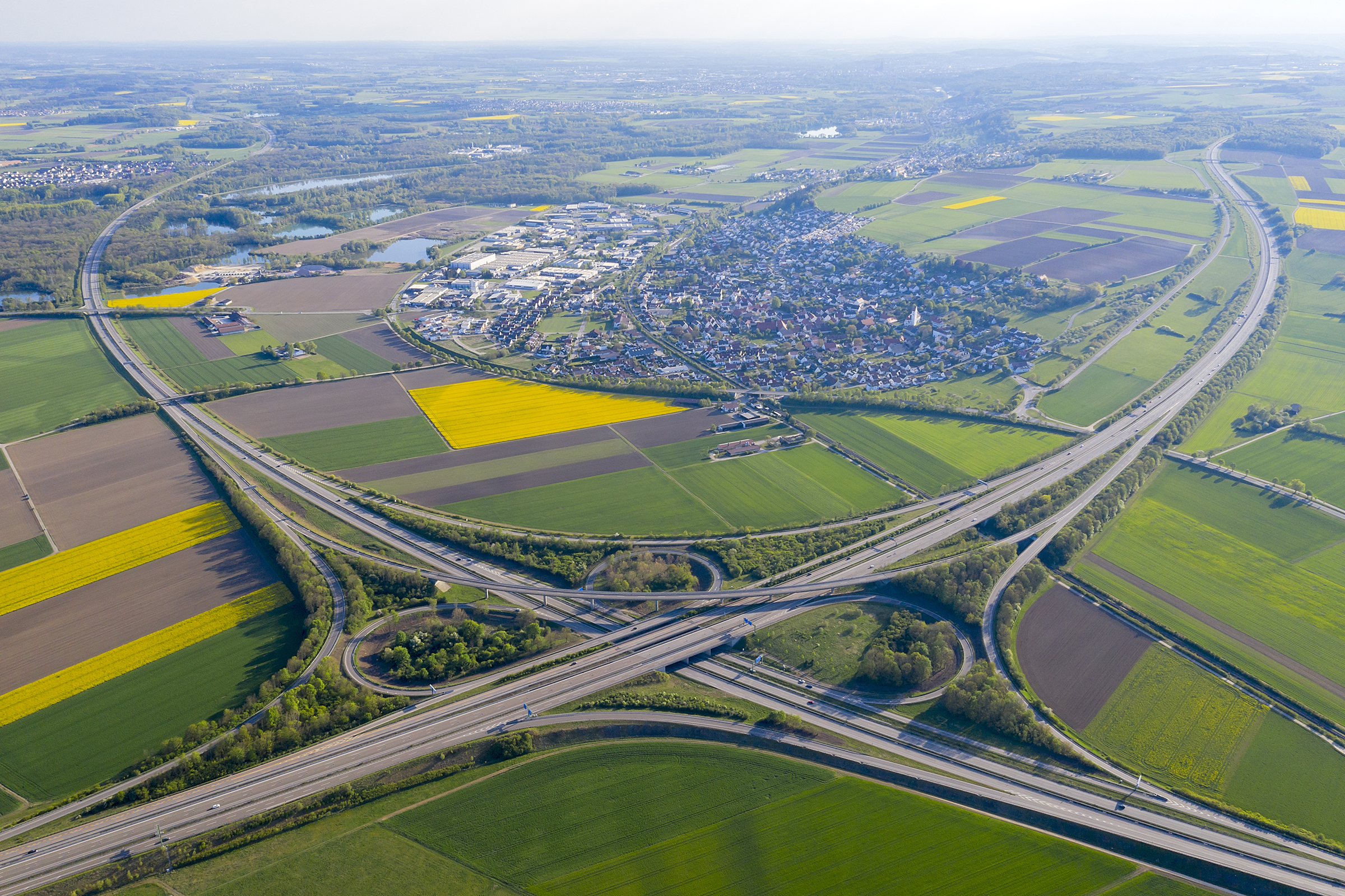Cross of two motorways surrounded by fields and a town in the background