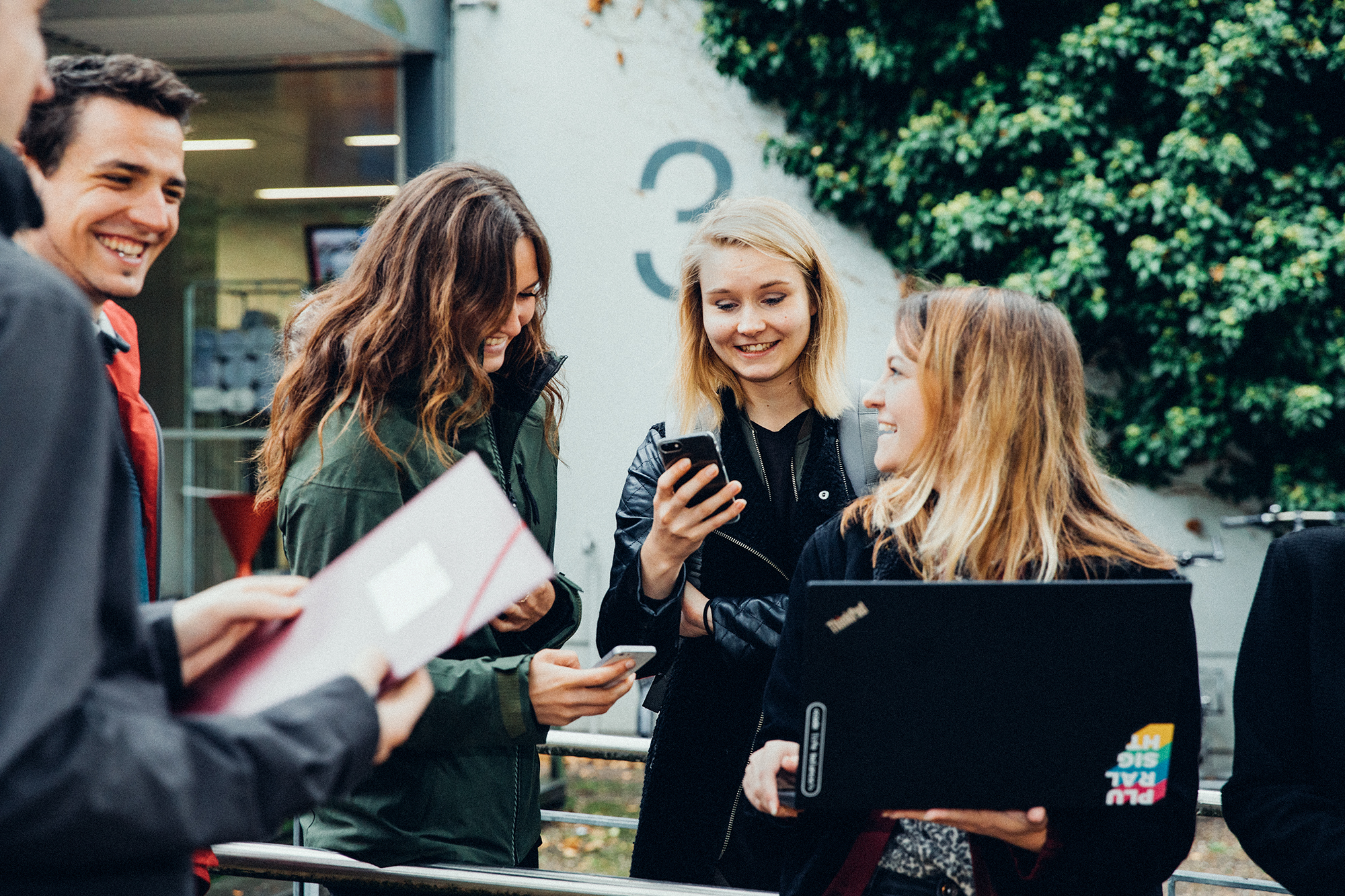 Gruppe junger Menschen mit Smartphones und Tablets auf dem Campus