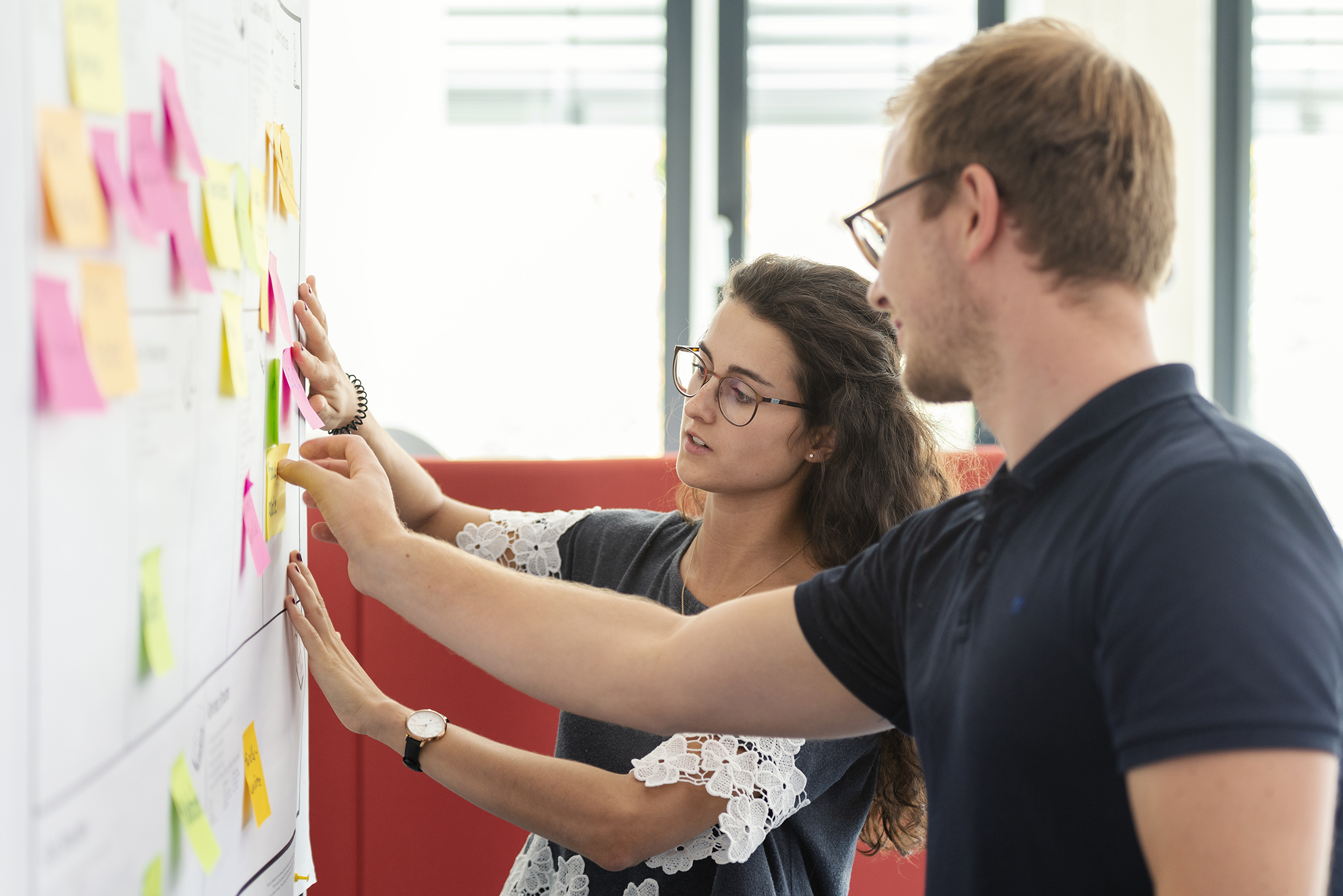 two students sticking post-its on a whiteboard