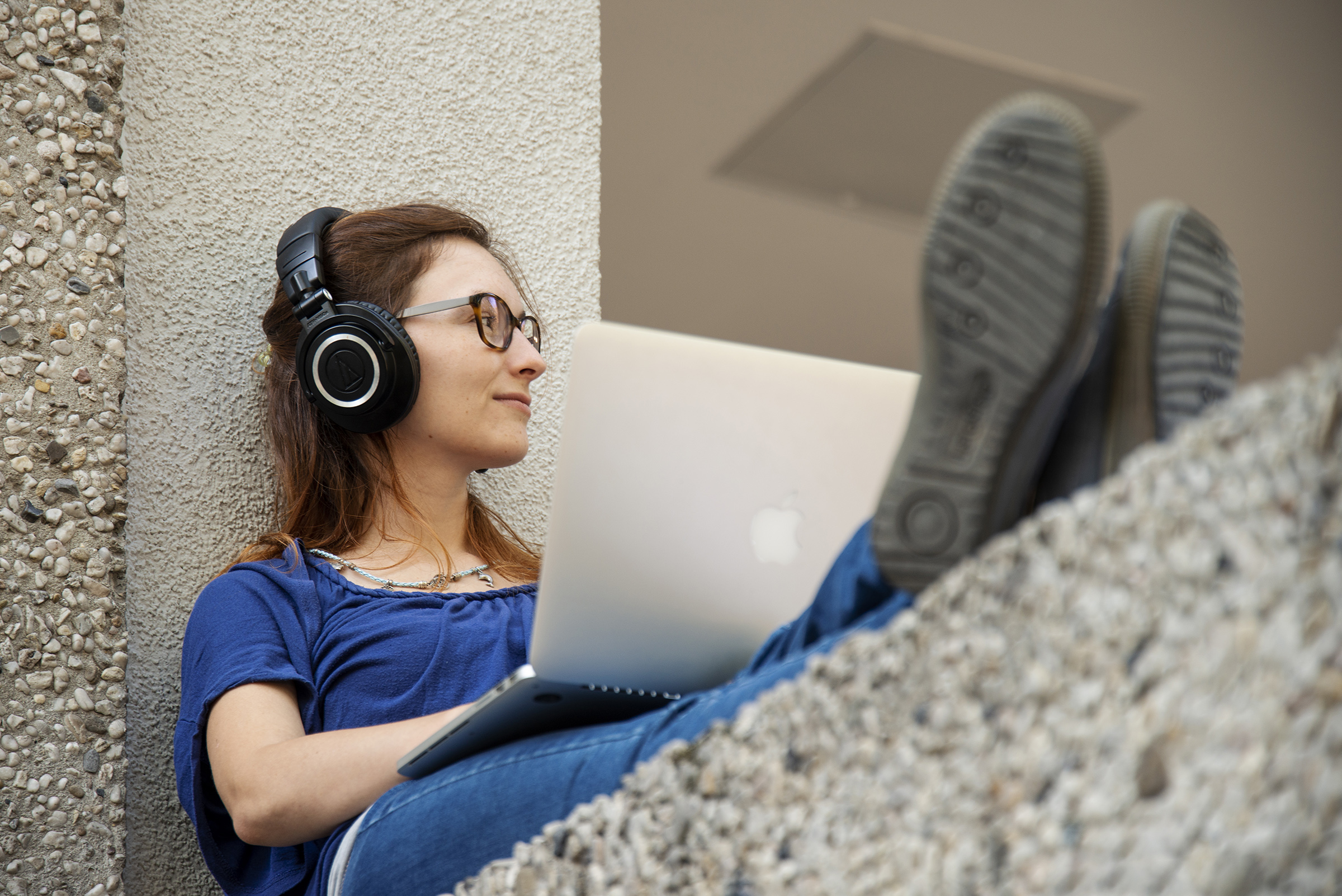 young woman working at laptop, while being relaxed and wearing earphones