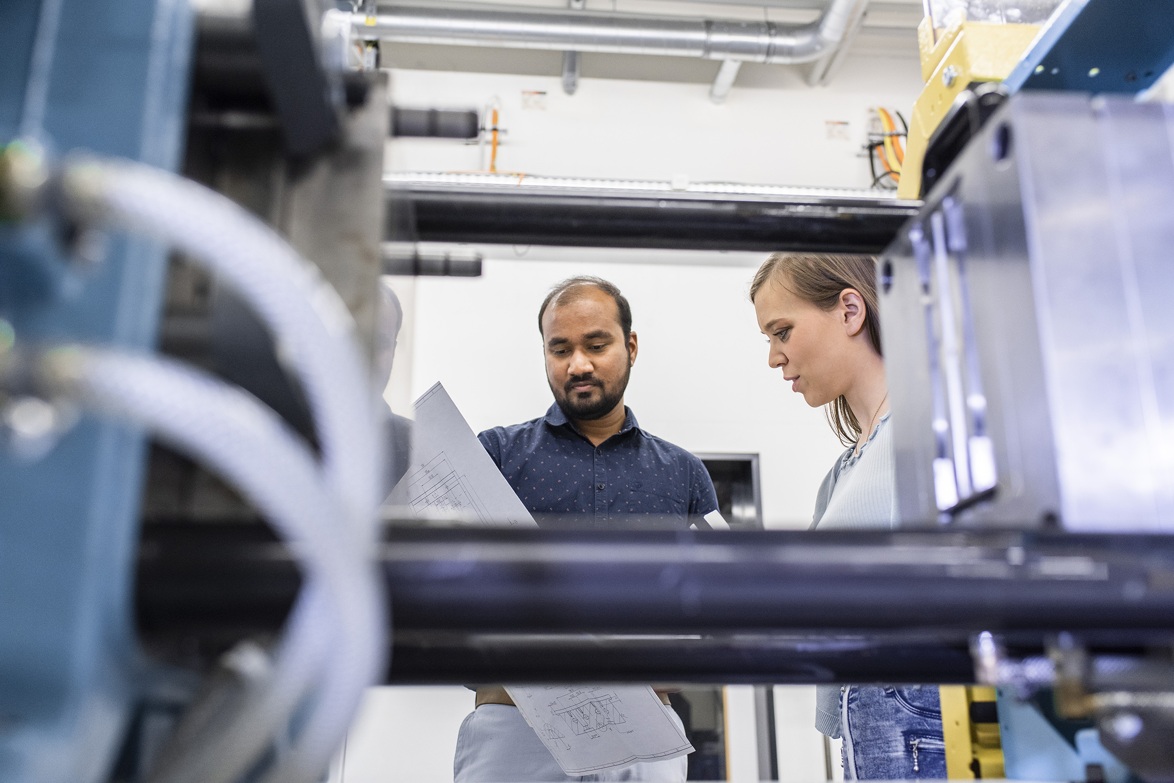 two people looking at a piece of paper, with machine in foreground