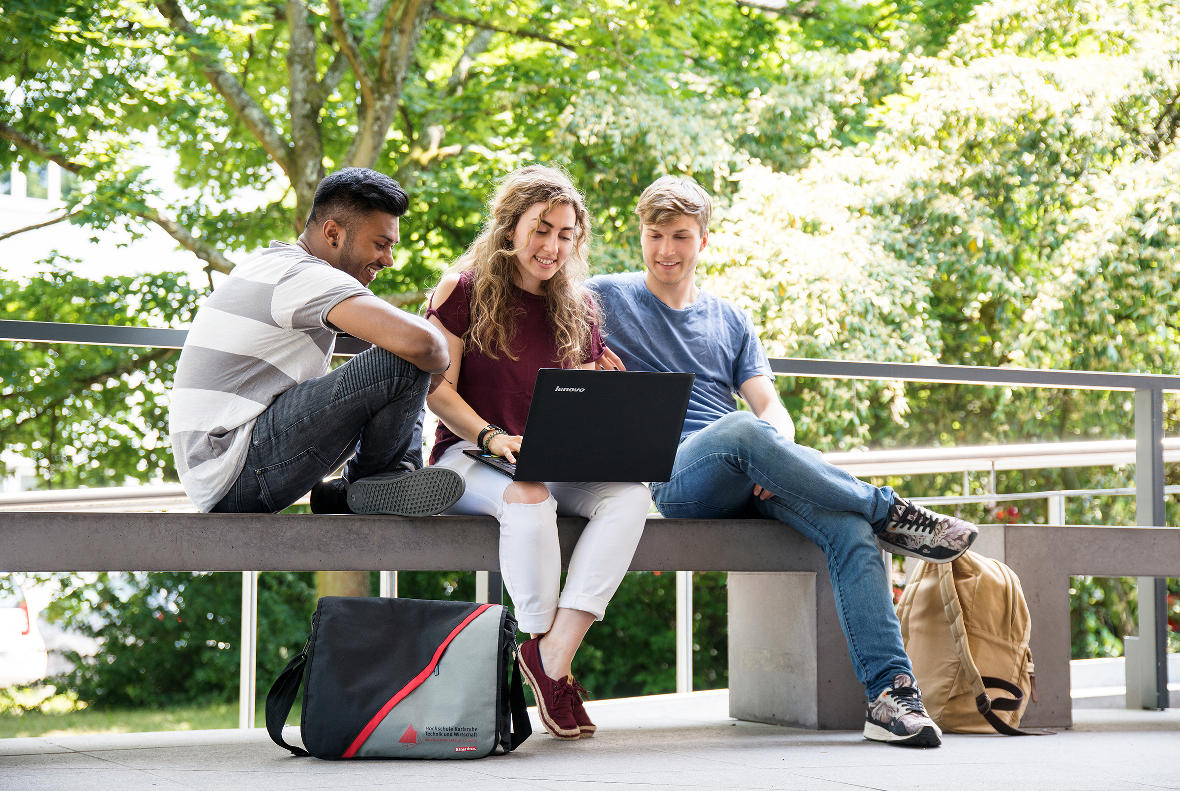 International students sitting outdoors with a laptop