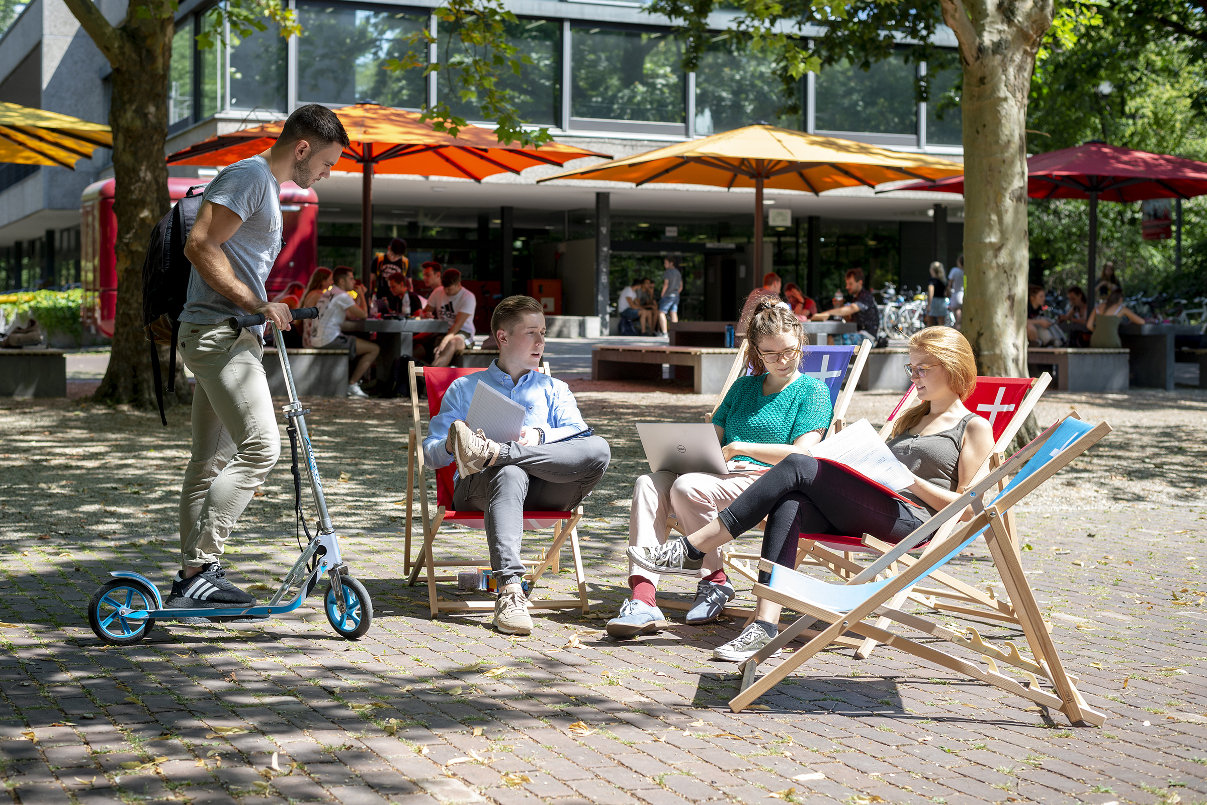 students sitting on HKA deckchairs under the sunshades on campus students sitting on HKA deckchairs under the sunshades on campus