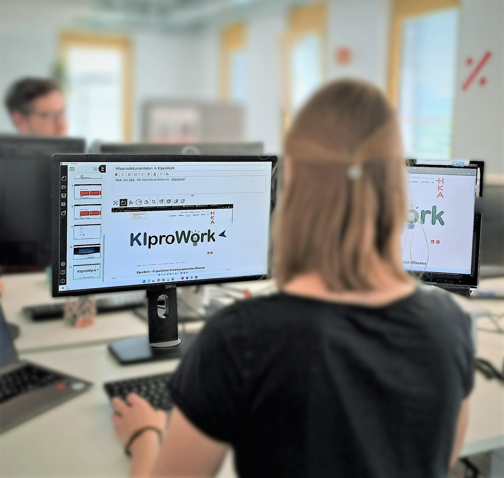 Betriebliches Wissen sichern und durch Künstliche Intelligenz für Unternehmen erhalten Mitarbeitende im Büro bei der Arbeit am PC