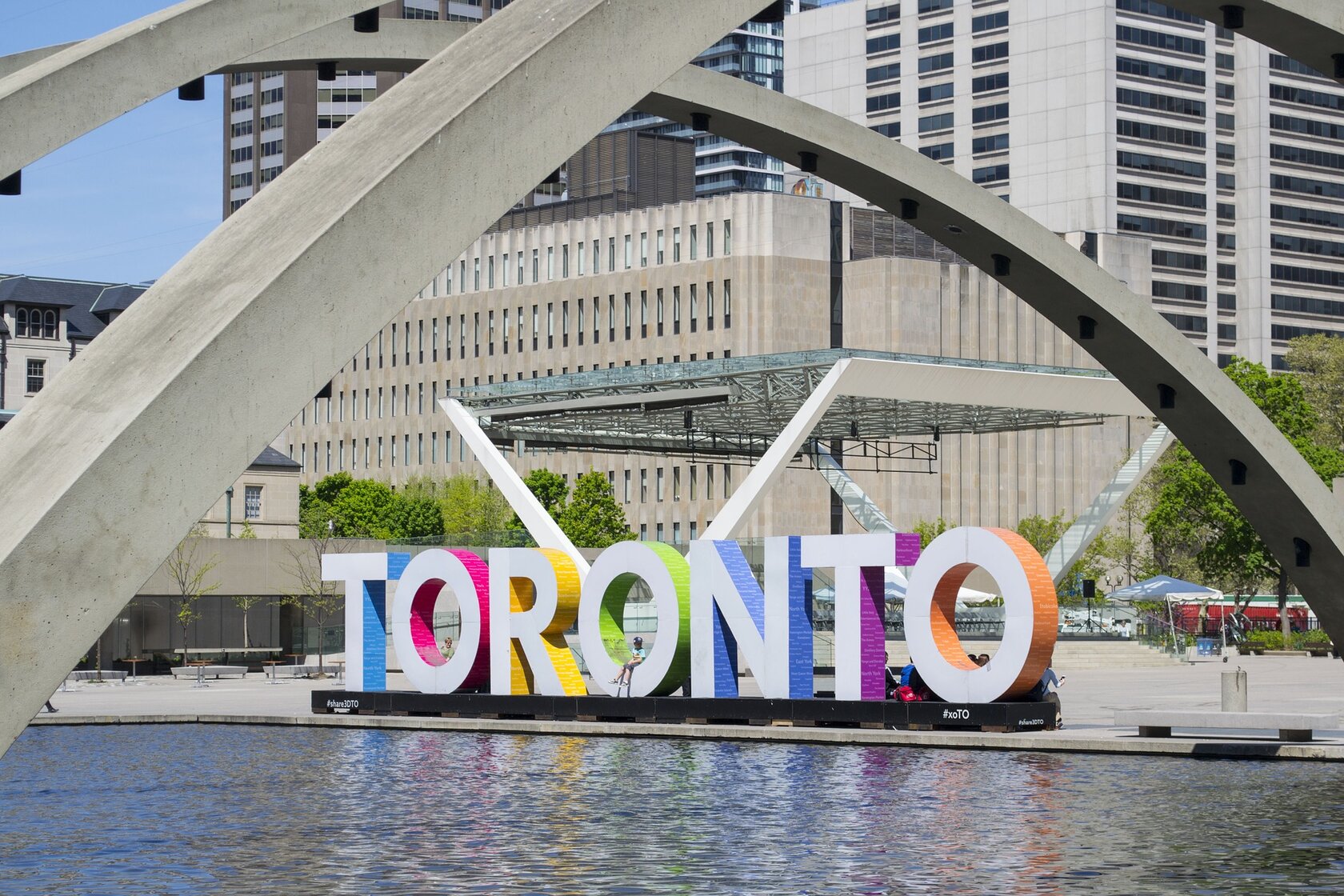 square in Toronto with a water basin and sculpture saying "Toronto" in front of buildings