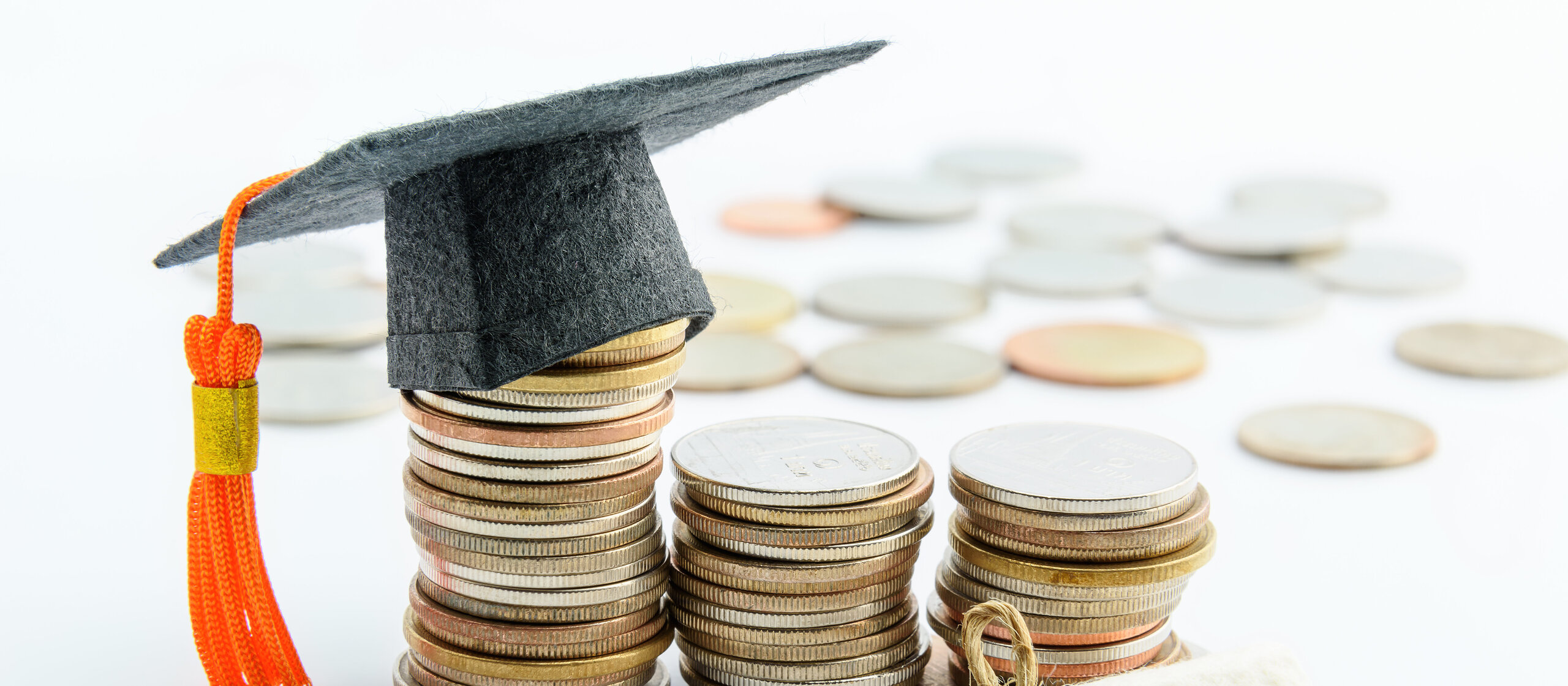Money cost saving or money reserve for goal and success in school, higher level education concept : US dollar coins / cash, a black graduation cap or hat, a certificate / diploma on white background.
