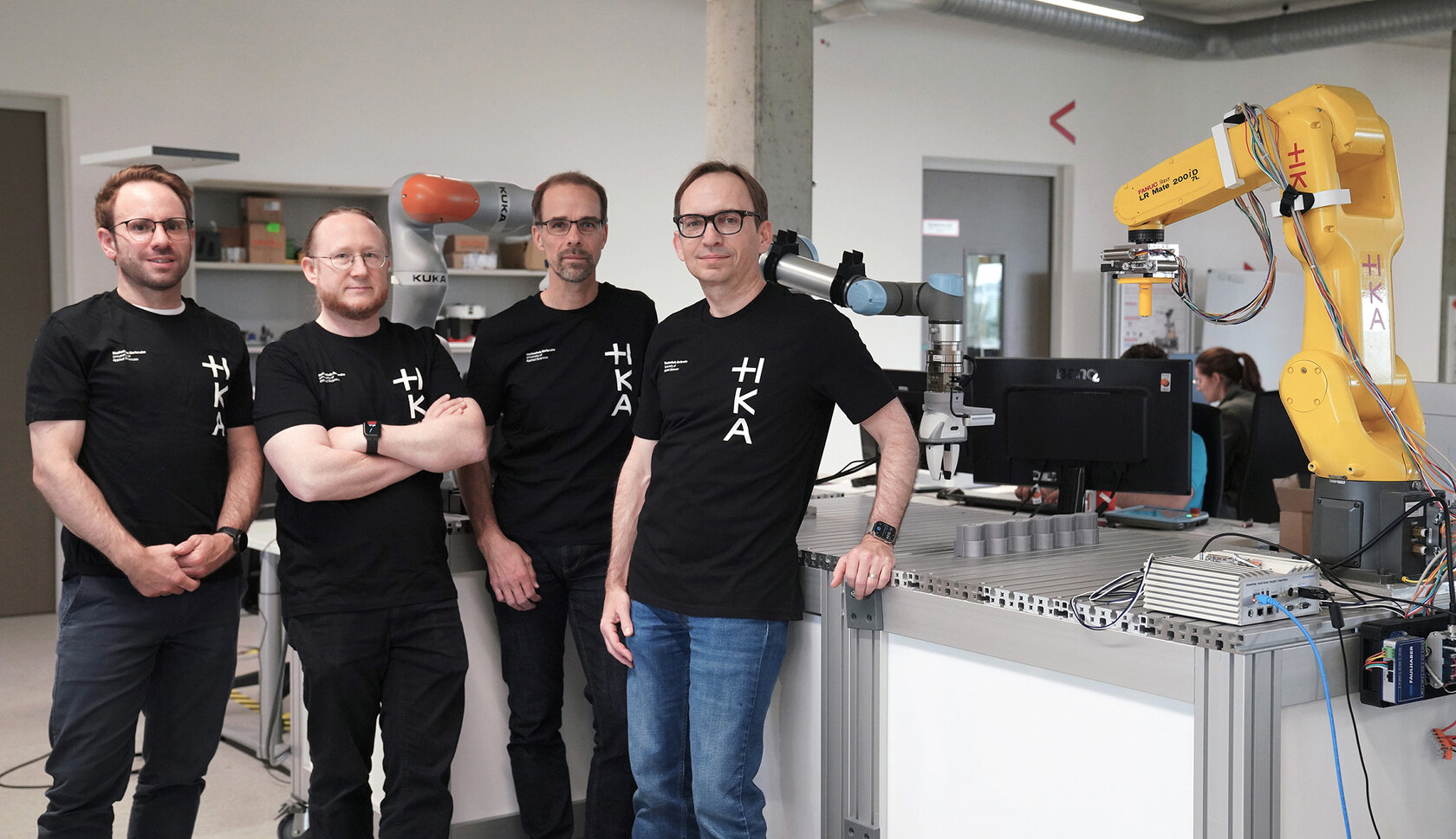 An der HKA entsteht eine neue KI-Plattform, mit der Roboter unternehmensübergreifend lernen können Im Projekt FEATHER forscht ein interdisziplinäres Team der HKA daran, durch föderiertes maschinelles Lernen robotische Systeme verschiedener Unternehmen zu trainieren – direkt vor Ort und ohne Weitergabe sensibler Daten. V. l. n. r.: Christian Friedrich, Björn Hein, Christian Zirpins und Oliver Waldhorst