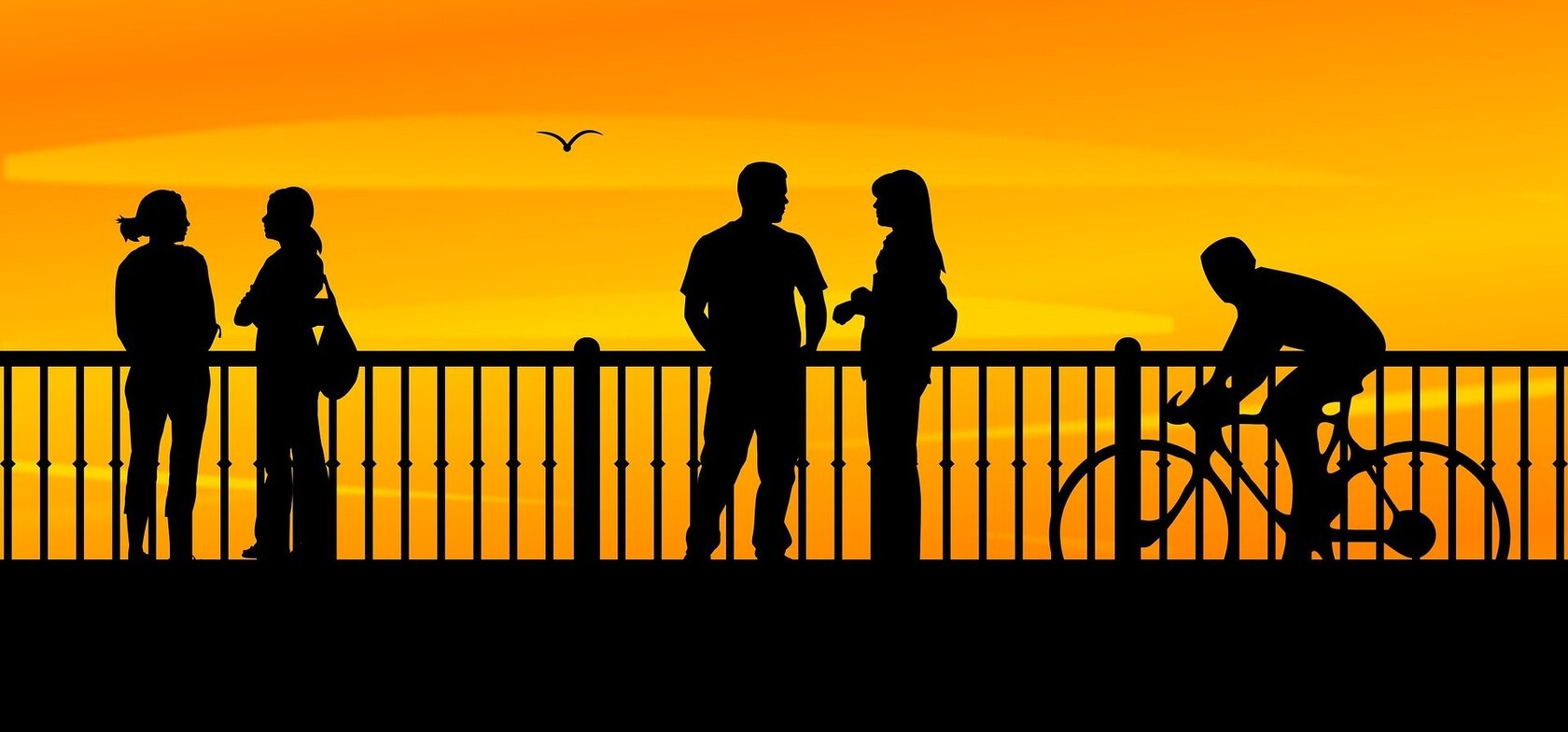 silhouettes of a group of young people on a promenade against sunset