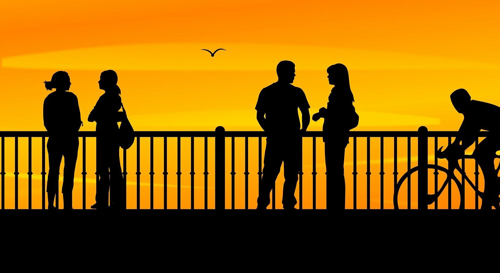 group of young people on a promenade silhouetted against sunset