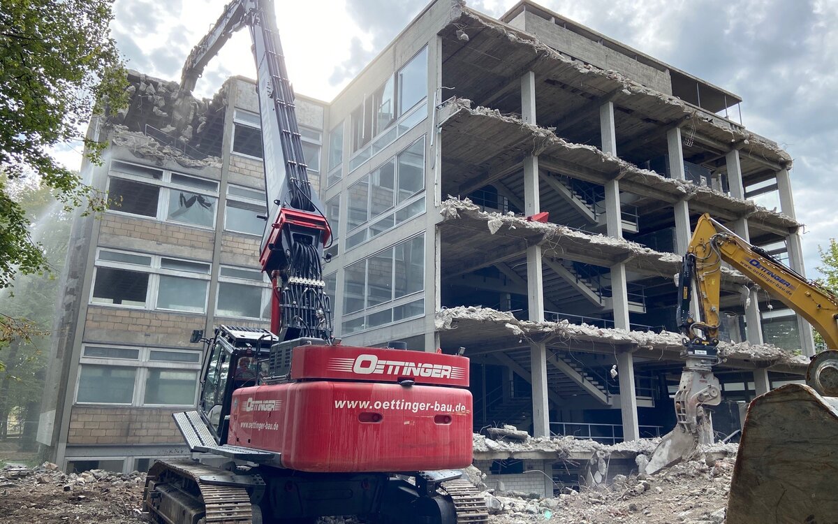 two excavators dismantling the building, a wall is missing