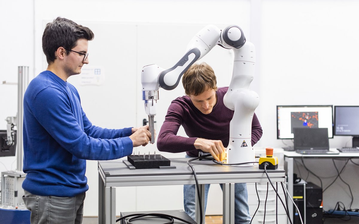 Fakultät für Maschinenbau und Mechatronik: 2 Studierende an einem Industrieroboter