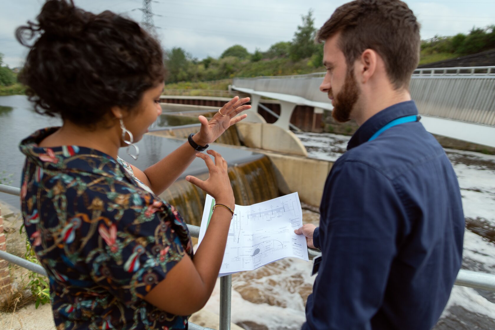 two engineers discussing a project, with a dam in the background