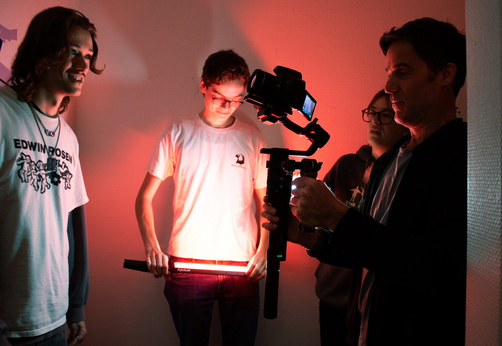 Prof. Krügler mit Studierenden in Action, sie halte eine Kamera und ein rotes Licht in den Händen