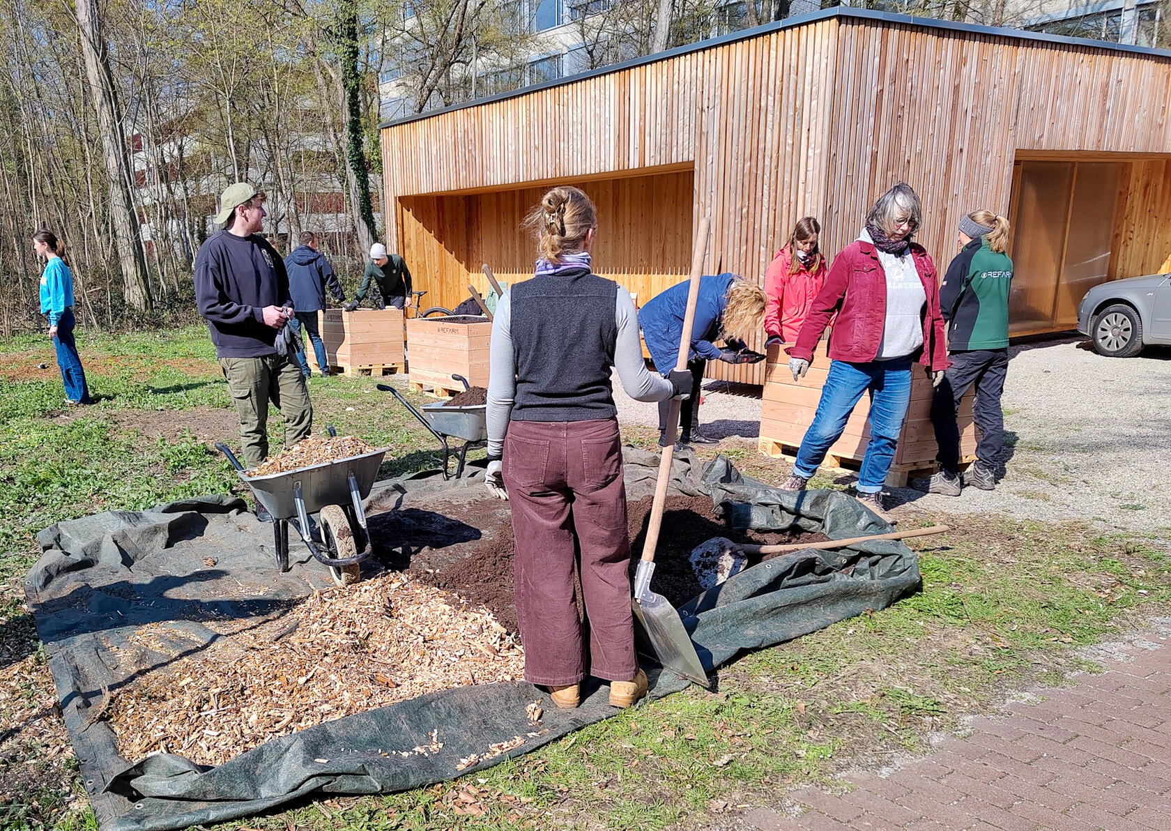 Foto von Menschen die gemeinsam an den Hochbeeten arbeiten.