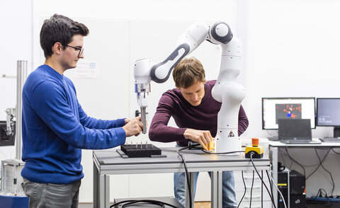 Studierende bei einer Projektarbeit mit einem Roboterarm