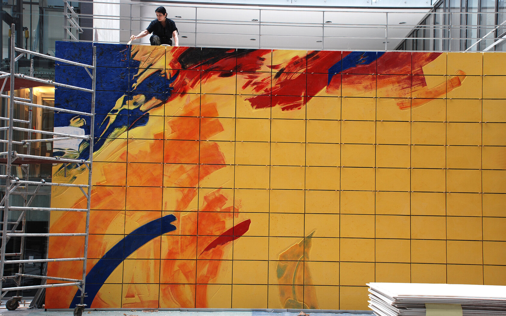 Female artist completing a large painted relief wall consisting of ceramic tiles in a bank lobby.Please see other pictures from this artist: