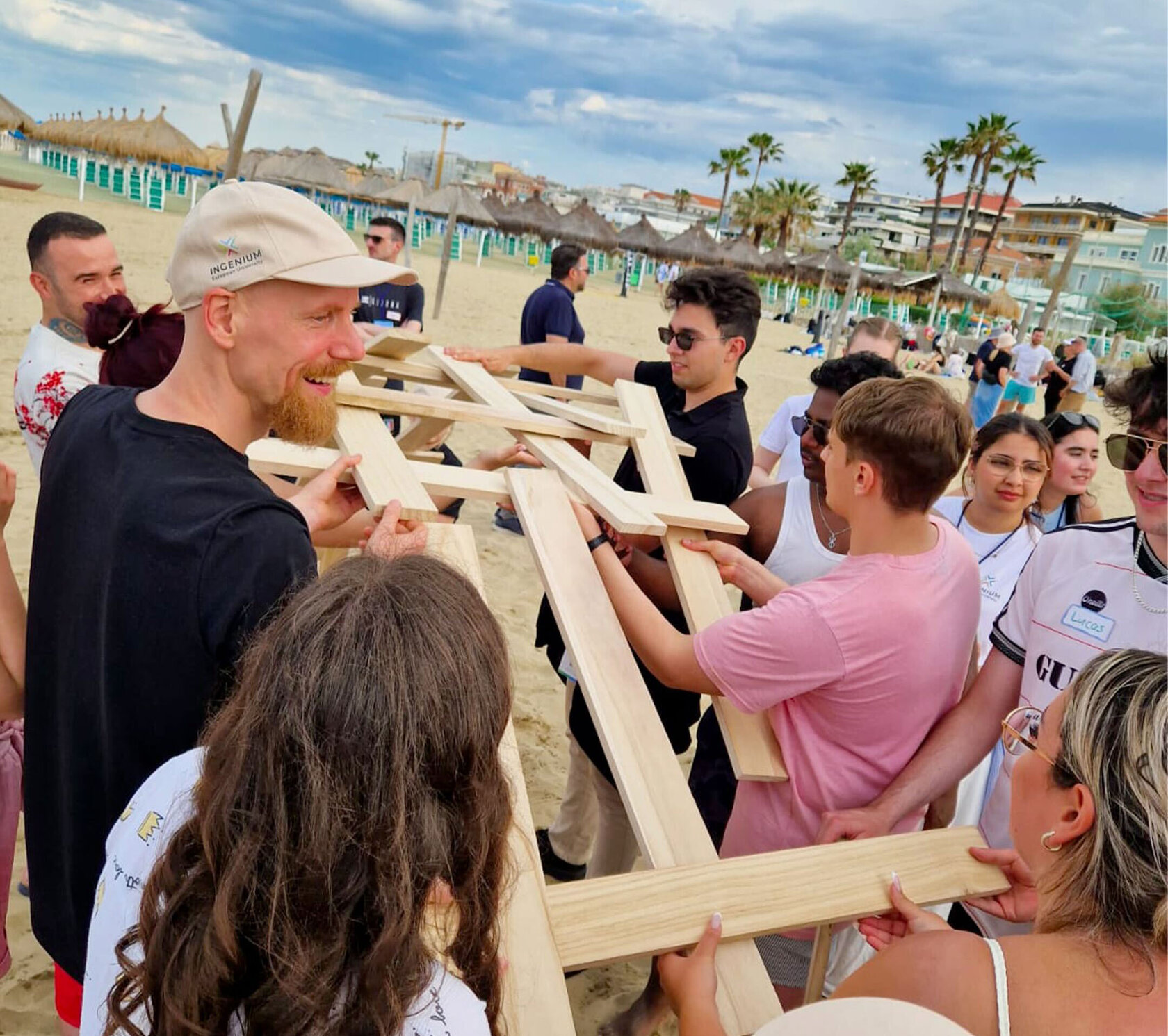 Studierende bauen eine Brücke aus Holzstangen am Strand
