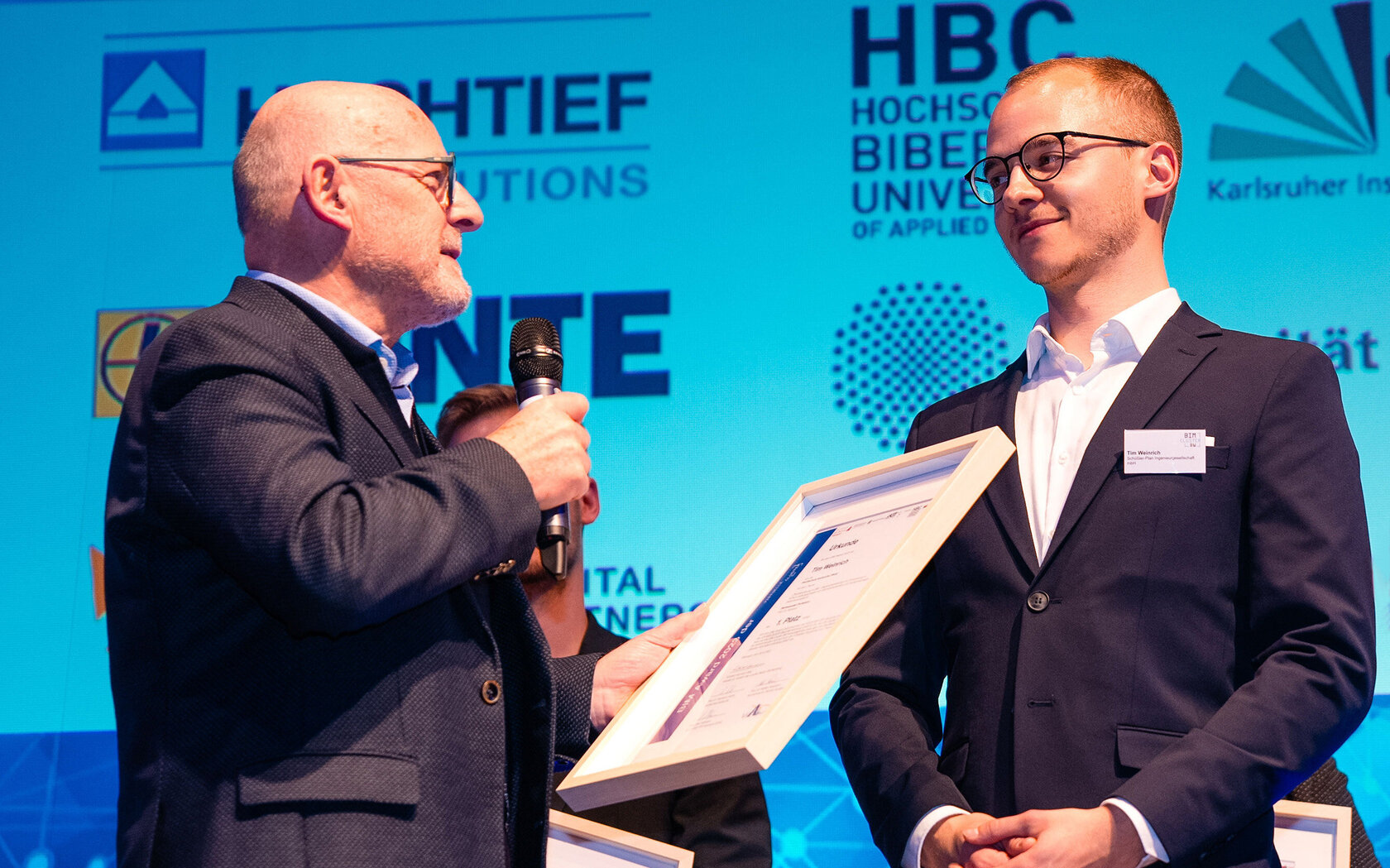 1. Preis beim BIM Award für Tim Weinrich (r.), Absolvent des Masterstudiengangs Bauingenieurwesen an der HKA, übergeben von Verkehrsminister Winfried Hermann 