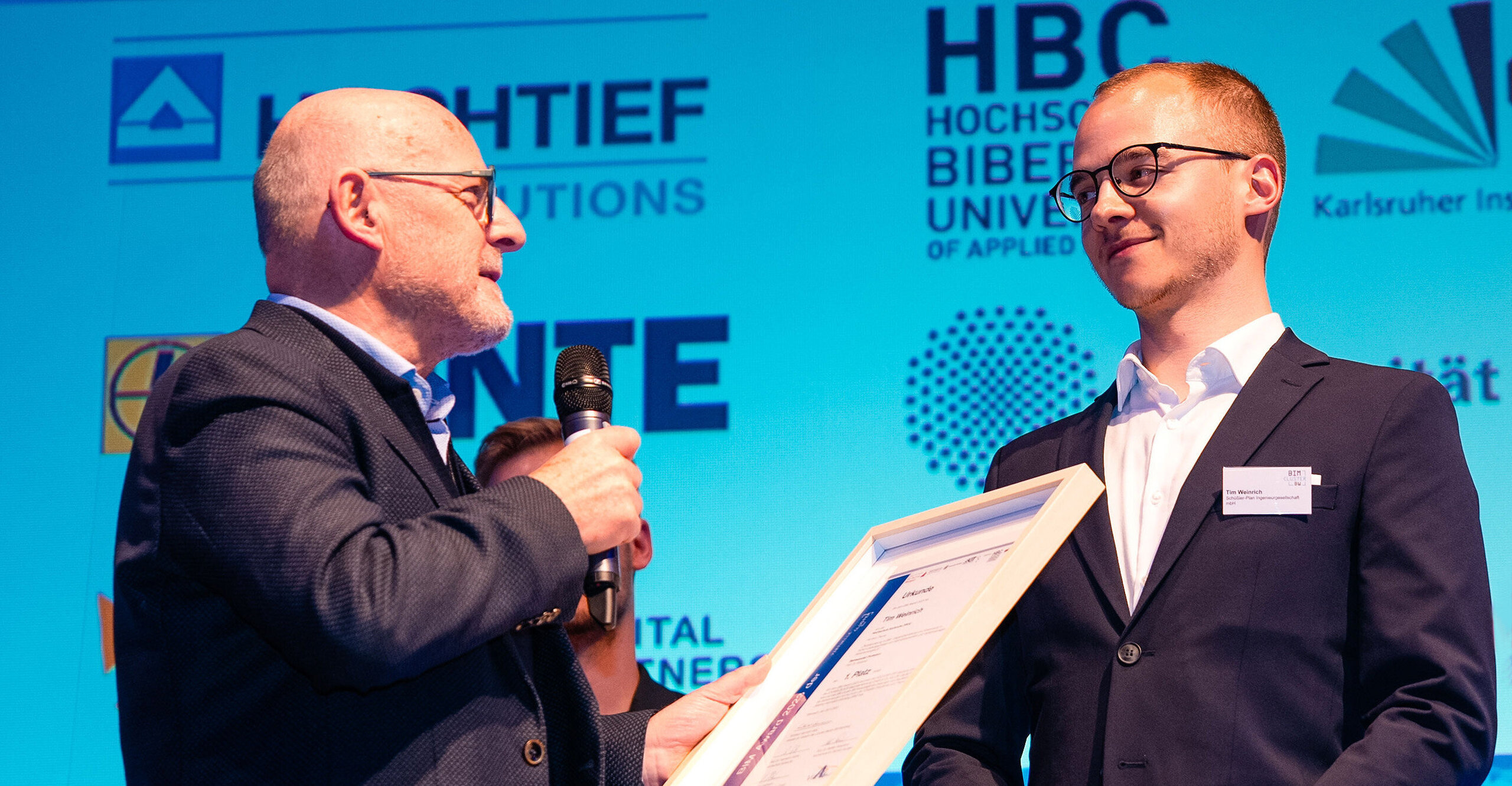 1. Preis beim BIM Award für Tim Weinrich (r.), Absolvent des Masterstudiengangs Bauingenieurwesen an der HKA, übergeben von Verkehrsminister Winfried Hermann 