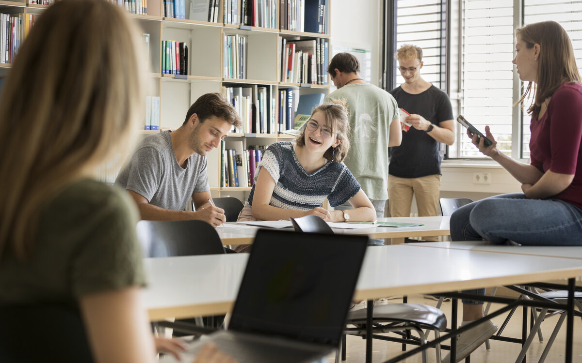 young people in the library, chatting and reading