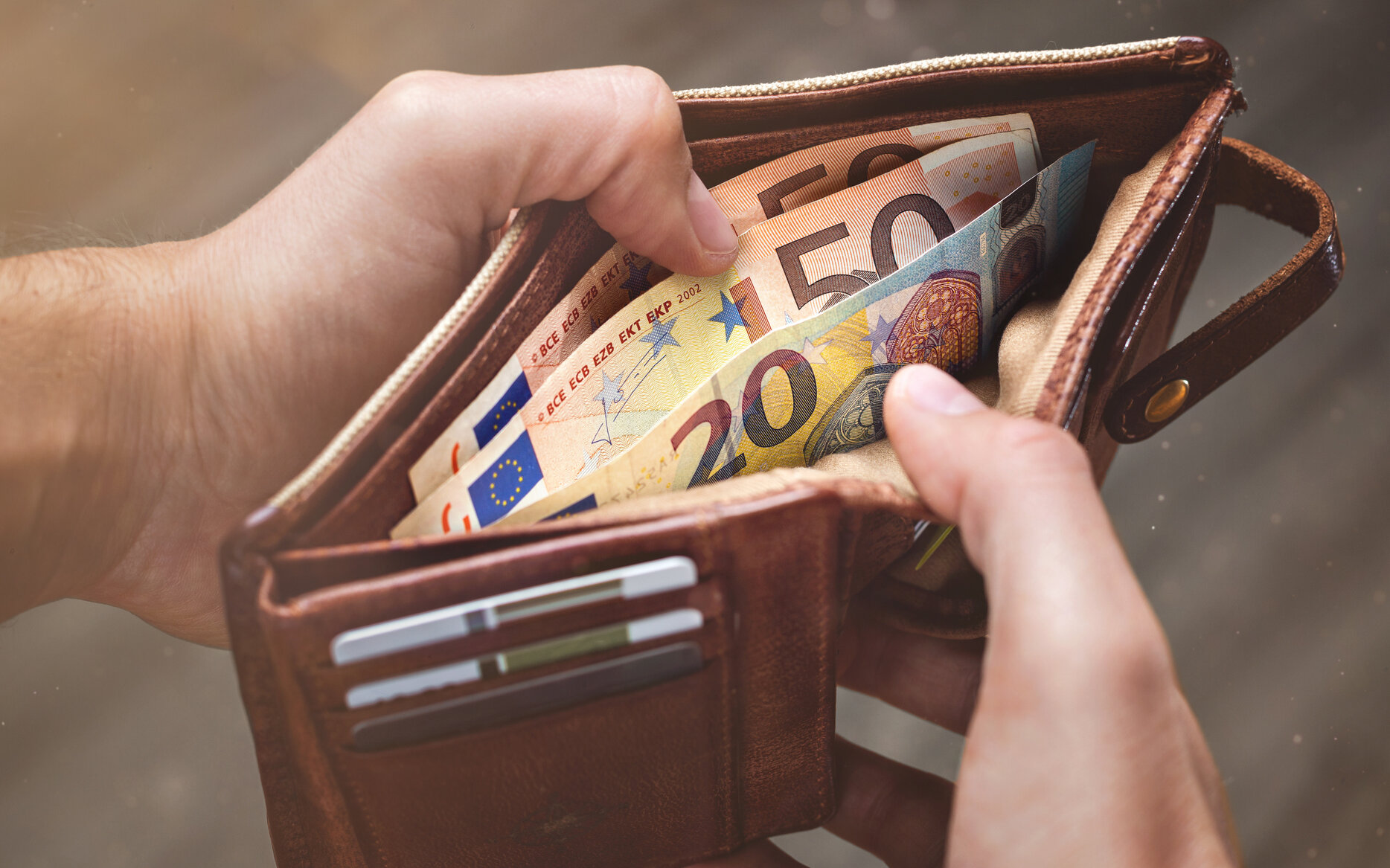 Hände öffnen eine Brieftasche mit Euro-Banknoten