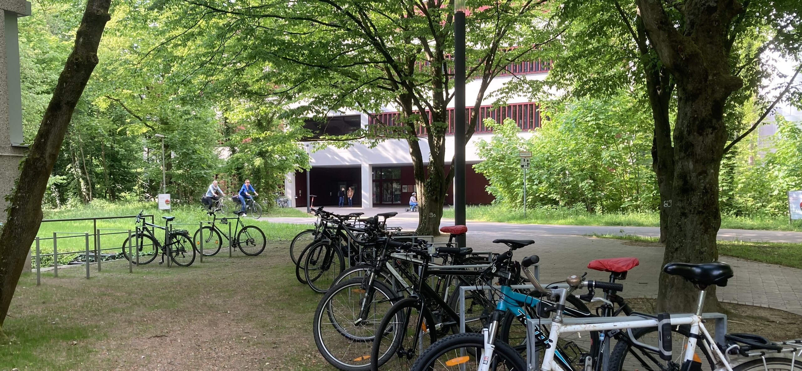 20220503_HKA_VW-EBI_jase_Fahrradstaender Fahrradständer im Vordergrund, zwei Radfahrer auf der Knielinger Allee im Hintergrund