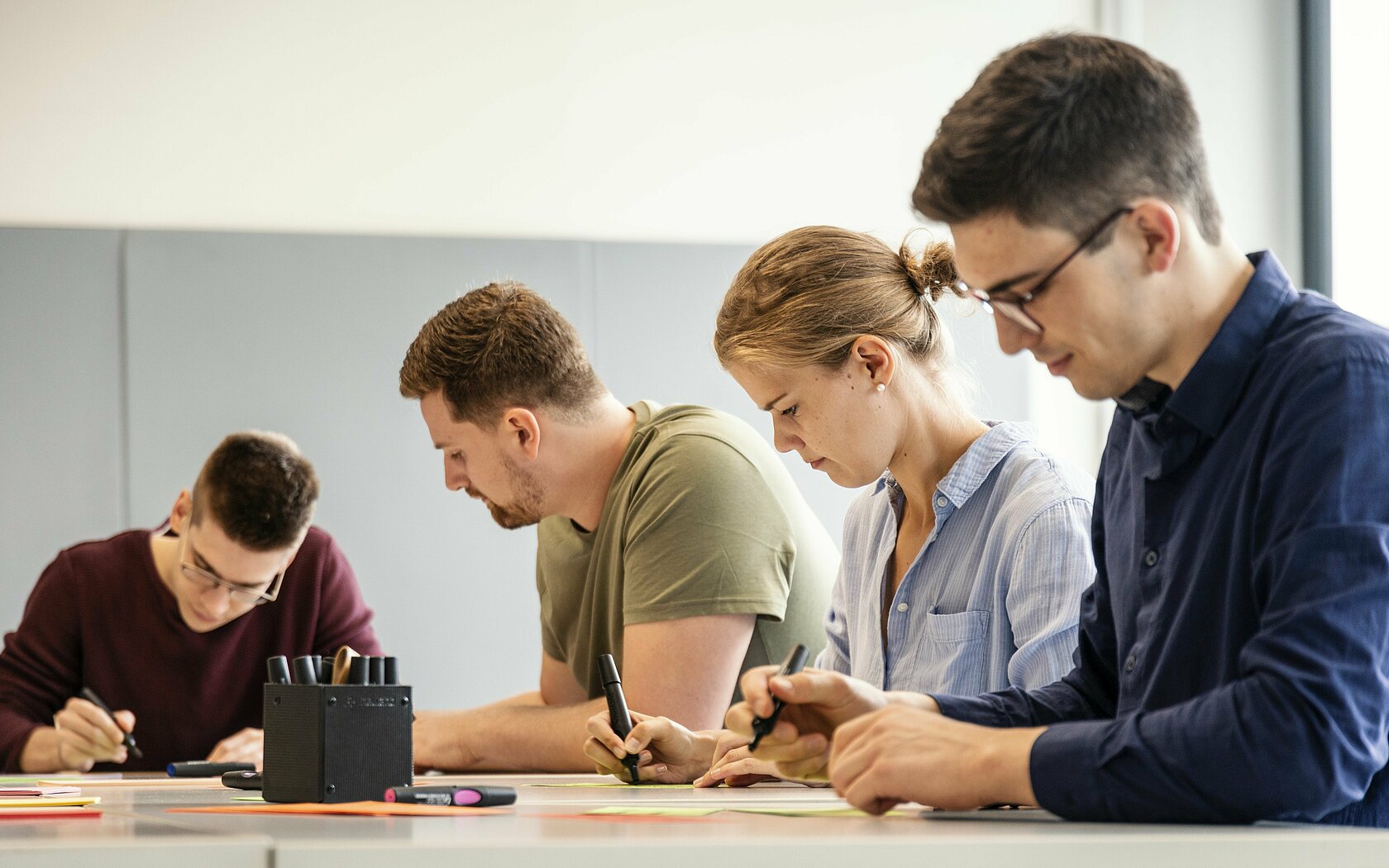 Vier Studierende sitzen an einem Tisch und lernen in einem Seminar