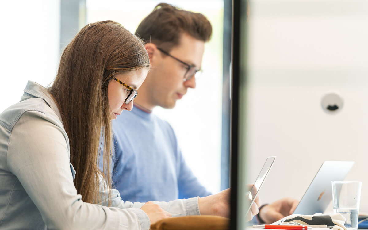 two students sitting next to each other with their laptops