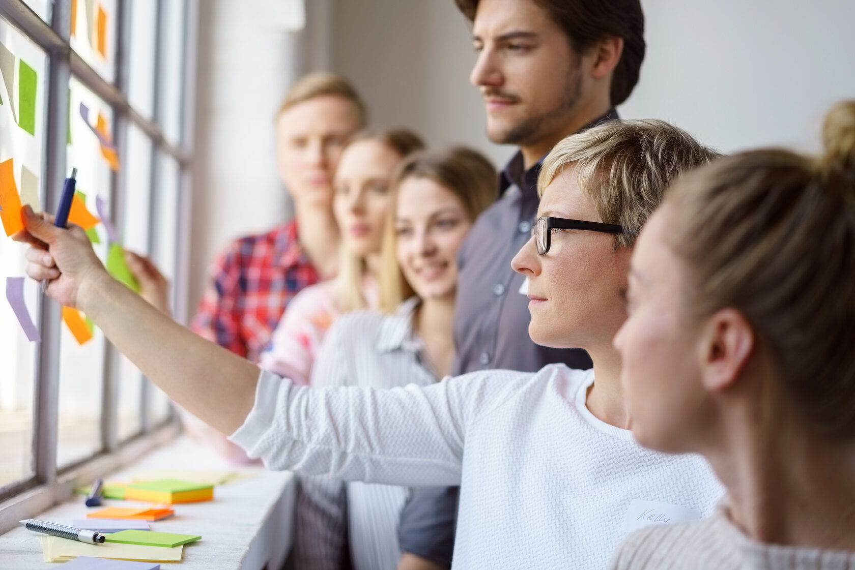 A team of focused work colleagues discussing ideas and brain storming with sticky notes on an office window. (A team of focused work colleagues discussing ideas and brain storming with sticky notes on an office window., ASCII, 109 components, 109 byte