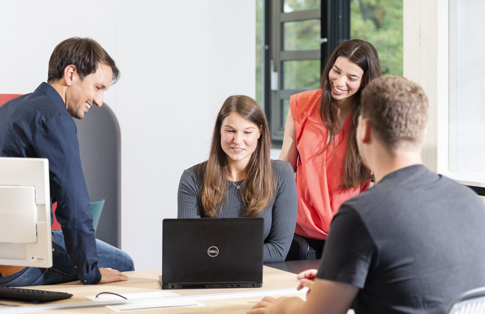 Dozent und 3 Studierende am Schreibtisch in Interaktion mit Notebook