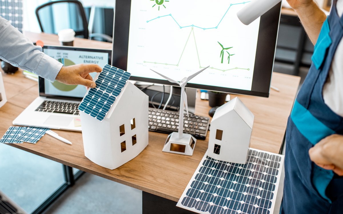 workspace with laptop and models of buildings and solar panels