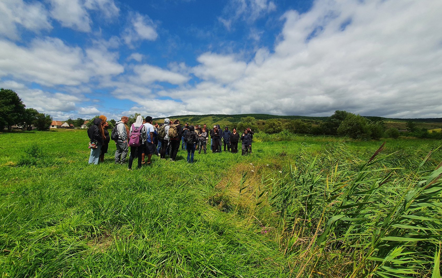 group of participants trecking across a meadow towards some hills