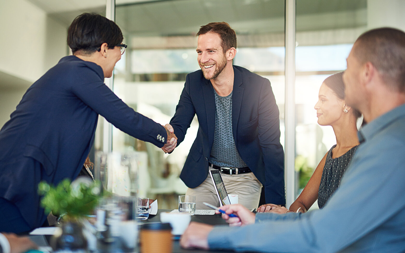 Handschlag zwischen zwei Menschen am Verhandlungstisch