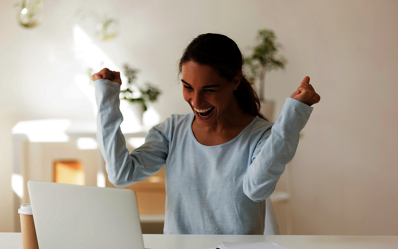 scholarship granted: young woman looks at her screen and rejoices scholarship granted: young woman looks at her screen and rejoices