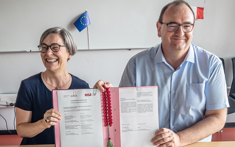 Prof. Beck and Prof. Boné sitting at a table, they present the signed agreement