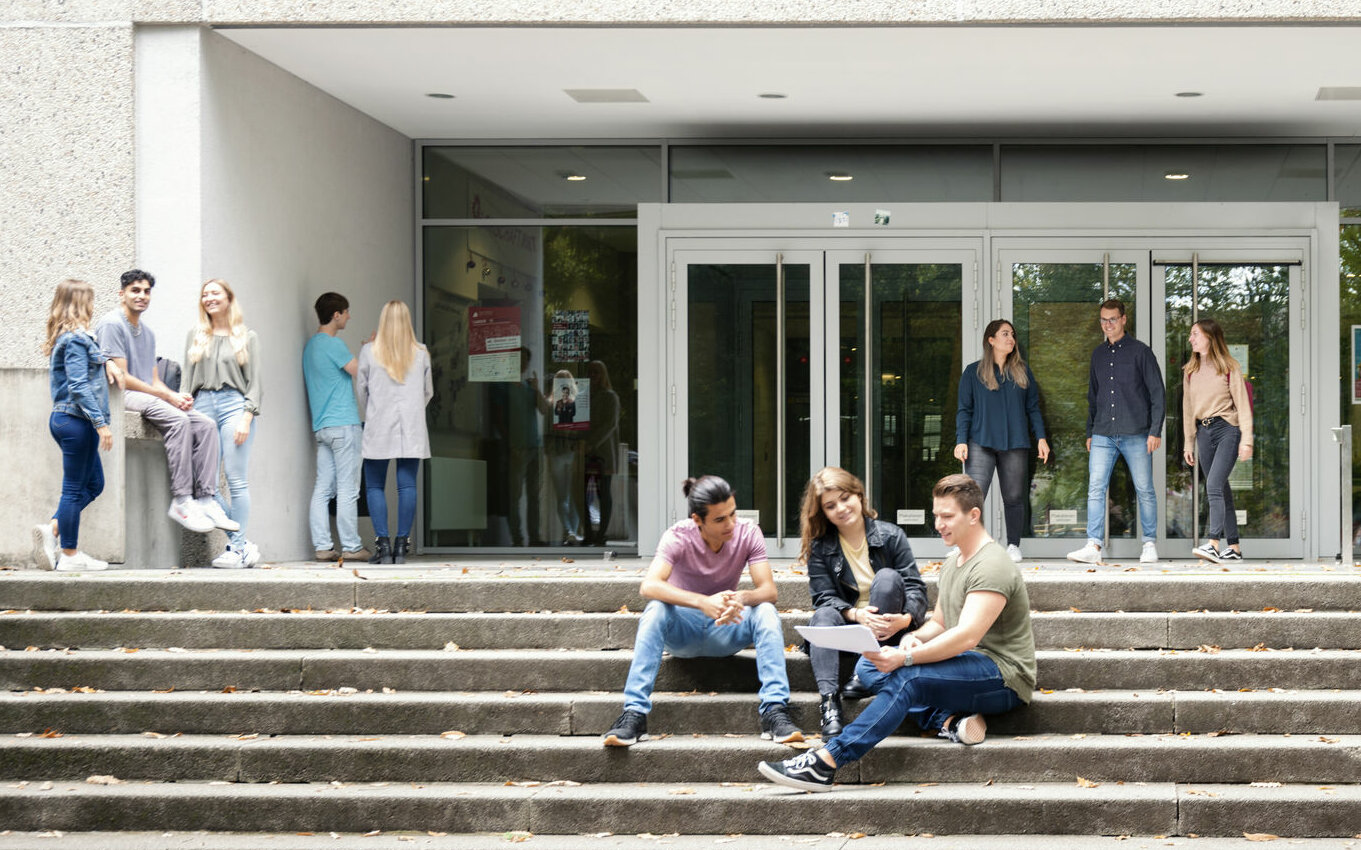Studierende halten sich vor dem Eingang der Hochschule Karlsruhe auf
