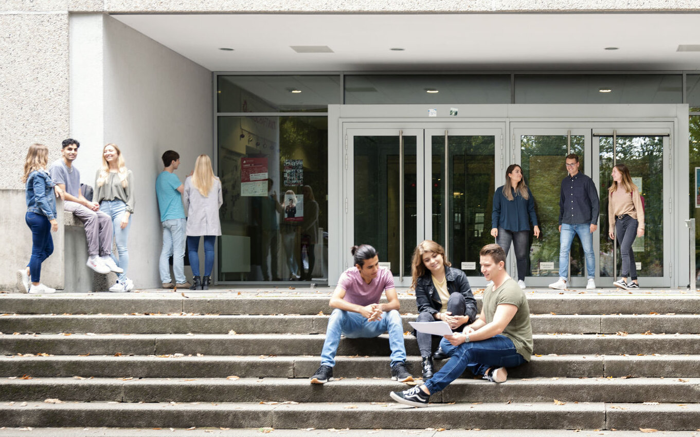 [Translate to English:] Studierende halten sich vor dem Eingang der Hochschule Karlsruhe auf