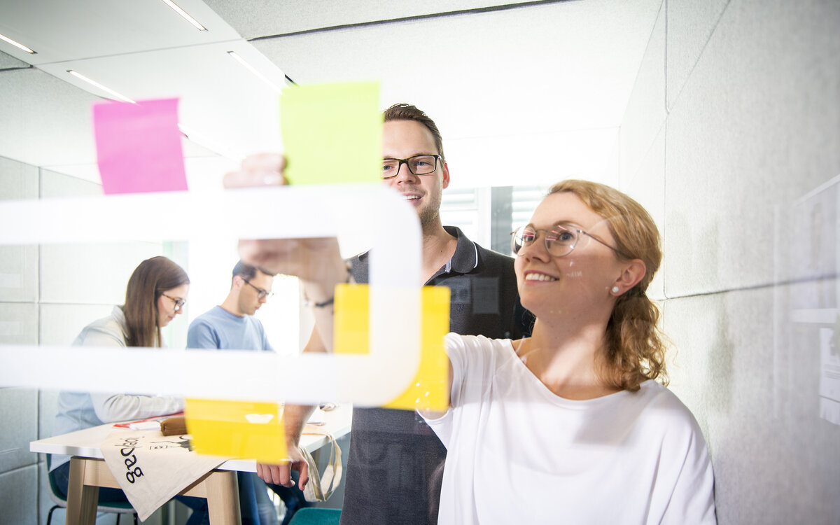 student workgroup pinning post-its on a transparent board