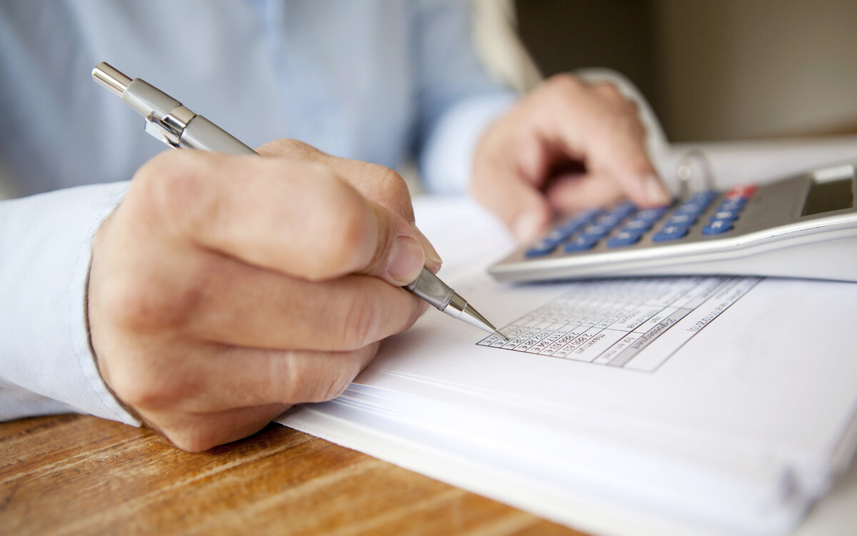 close-up of hand writing on paper, with pocket calculator in the background