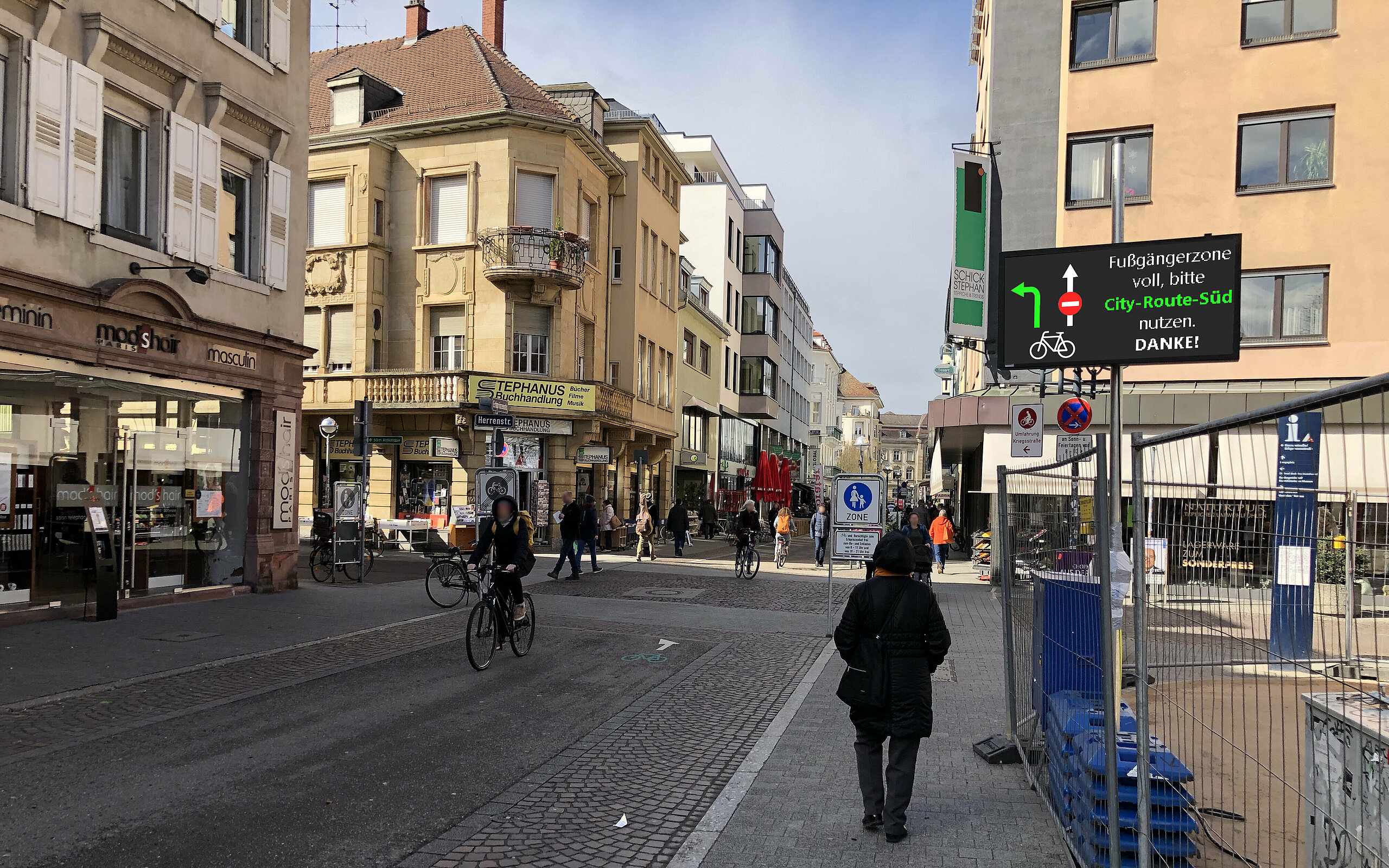 view of a street in Karlsruhe with shops, cyclists, and pedestrians