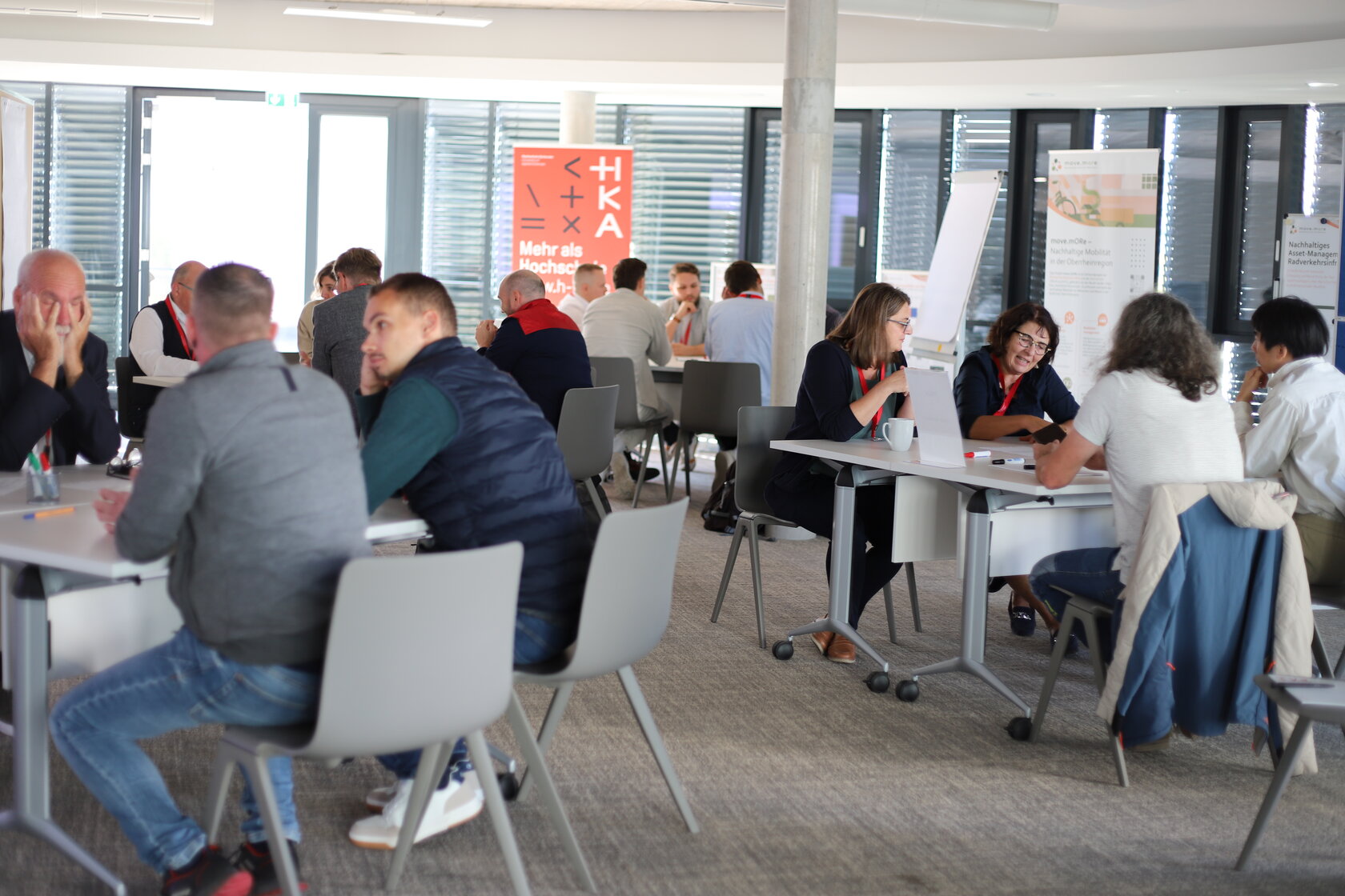 Teilnehmende sitzen in mehreren Gruppen an Tischen und tauschen sich beim World-Café zu Herausforderungen bei der Unter- und Erhaltung von Radverkehrsinfrastruktur aus.
