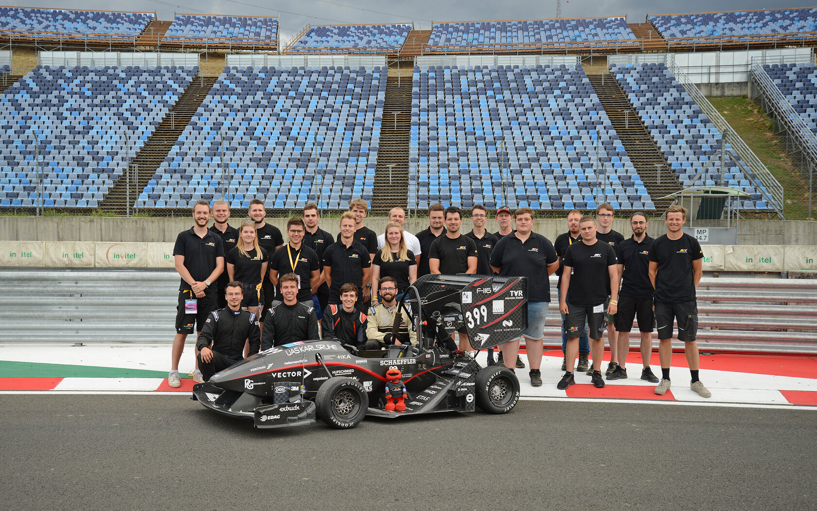 team standing behind the race car on the track