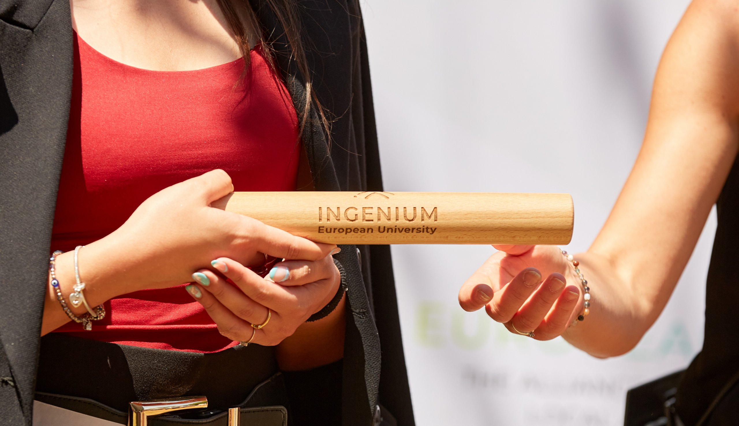 closeup of engraved INGENIUM baton passed from one person to the next