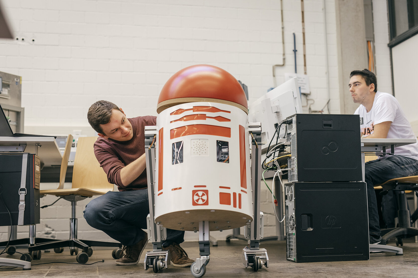 two students in the lab, working on a small robot